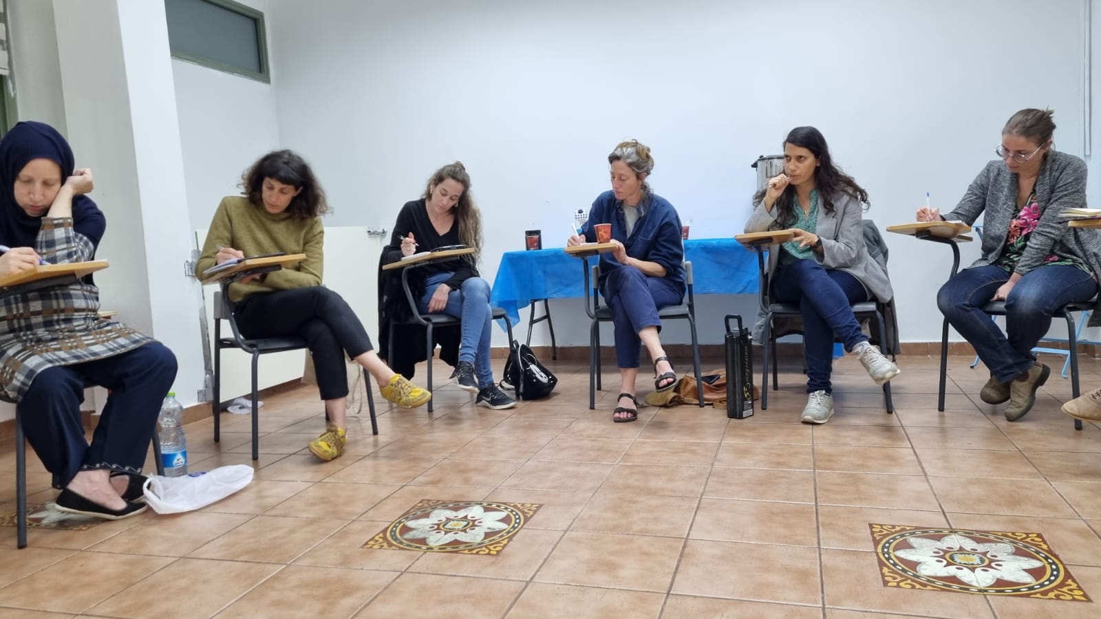 משתתפת כותבת ליד שולחן כחול